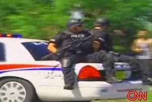 Cops on trunk of police car with assault rifles